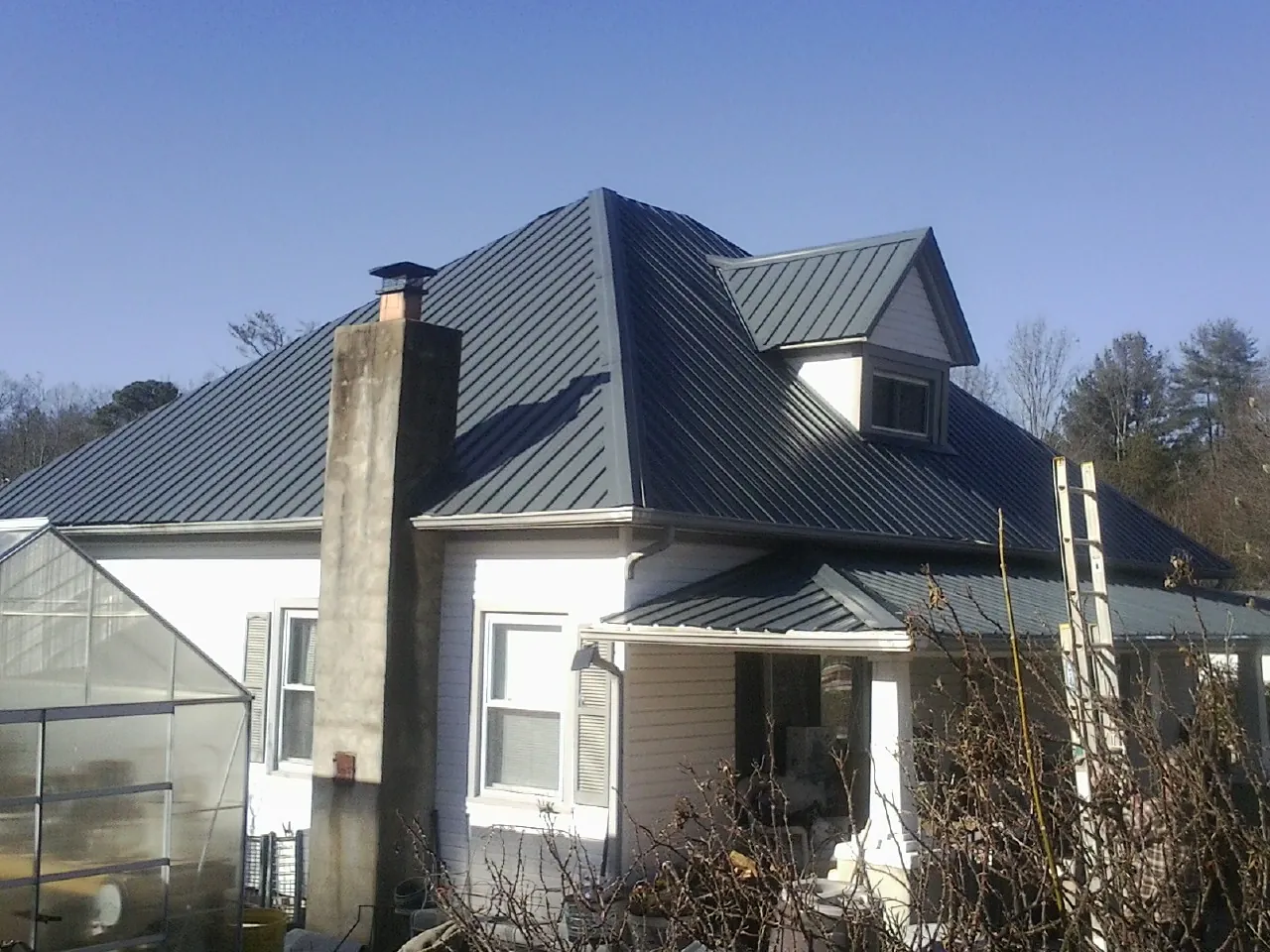 Dark blue standing seam metal roof on a white farmhouse with dormer — Slate & Tile Roof Repair by Roofing Brothers in Kensal
