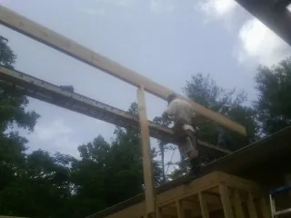 Carpenter setting a ridge beam over a new addition frame — Ice Dam Removal by Roofing Brothers in Kensal