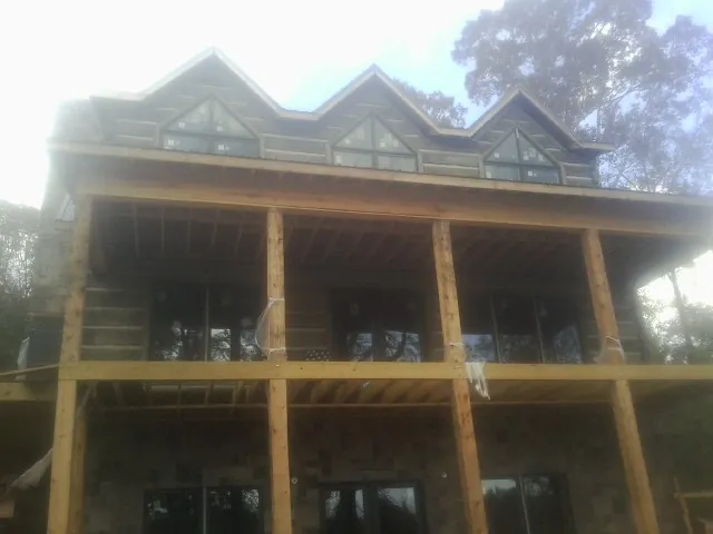 Dormers and porch framing on a large log home under construction — Roof Coating work by our crew in Kensal