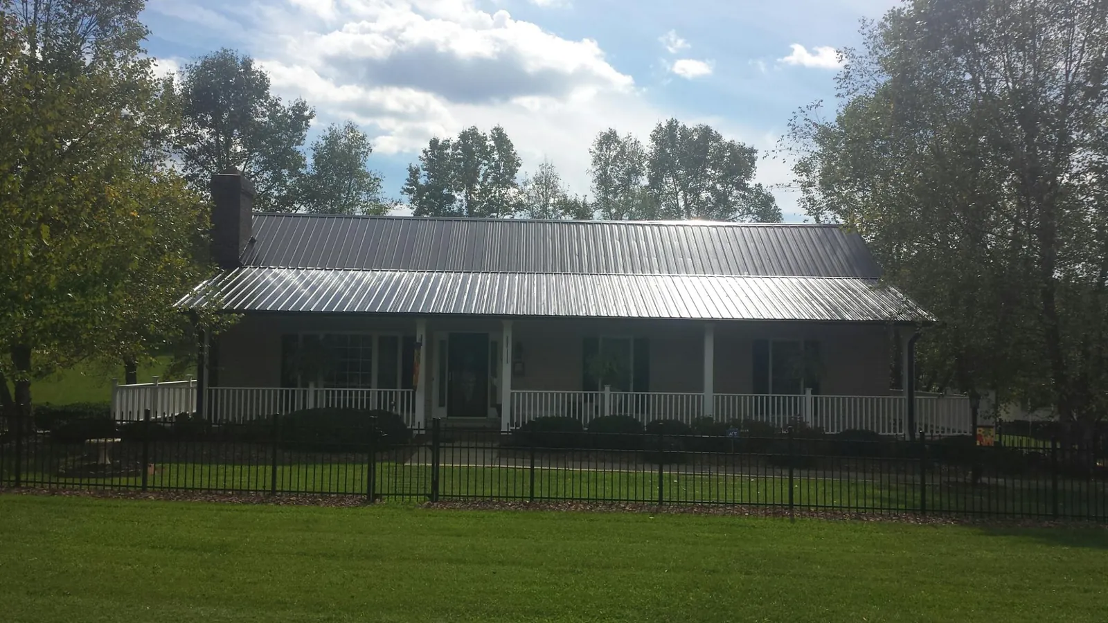Gray metal roof on a brick ranch with a full width front porch — Gutter Guard Installation work by our crew in Kensal